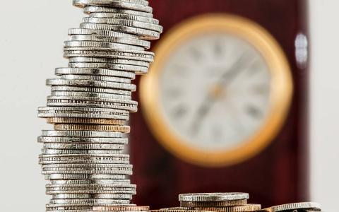 Stack of coins in front of a clock